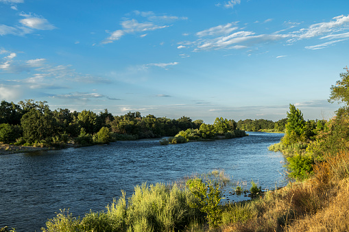 Wide shore view of Sacramento River with clouds in the background.\n\nTaken along the shore of the Sacramento River, River Bend Park, Sacramento, California, USA