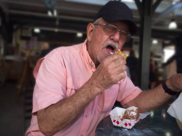 istock Senior Man eating Beignet in New Orleans 1583773629