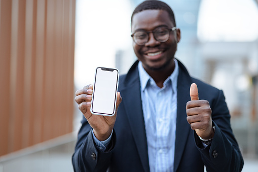 Portrait of African American good-looking man using smart phone and showing blank screen