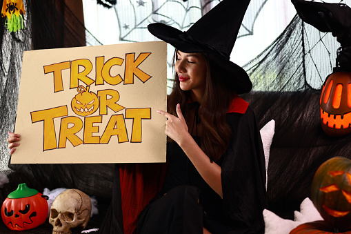 Attractive woman showing trick-or-treat signs at the Halloween party with Halloween products.