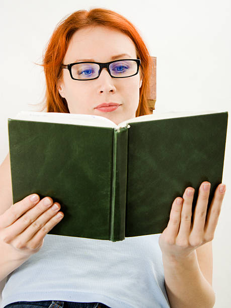 Young beautiful woman with red hair reading book