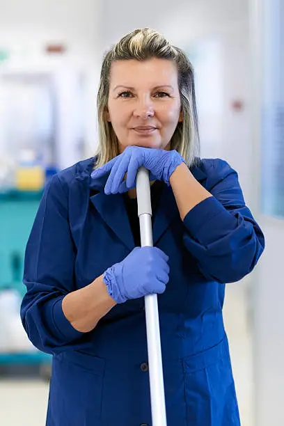 Women at work, portrait of happy professional female cleaner smiling and looking at camera in office. Three quarter length