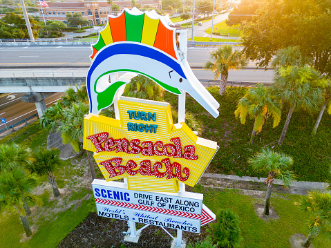 Pensacola Beach, FL, USA - July 21, 2023: Aerial photo of the Pensacola Beach road sign backlit at sunset
