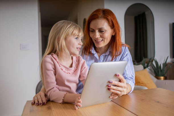 istock Cute little daughter and mother using digital tablet 1583949479