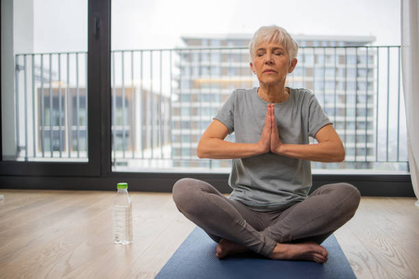 istock Senior woman sitting on the floor on exercise mat 1583951590