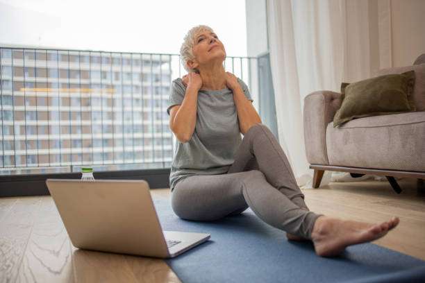 istock Senior woman sitting on the floor on exercise mat 1583951783