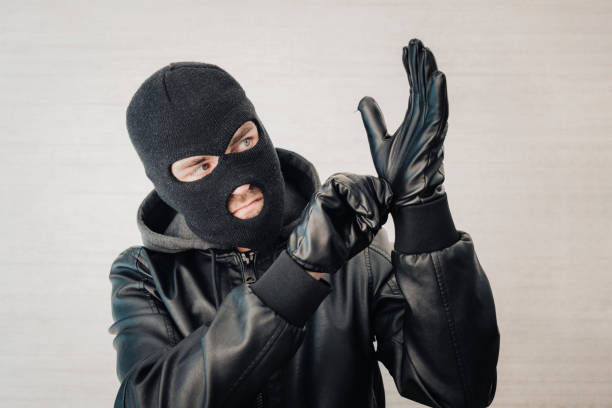 thief in a black jacket. A man in a black balaclava with an evil expression on his face. An aggressive bandit on a white background. The concept of crime or theft. A thief in a black jacket. A man in a black balaclava with an evil expression on his face. An aggressive bandit on a white background. The concept of crime or theft. wrongdoer stock pictures, royalty-free photos & images