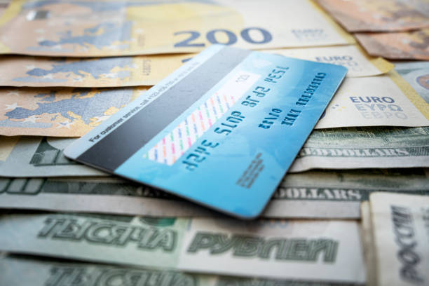 istock payment card on background of paper dollars. blue plastic multicurrency credit card is lying on stack of money euros rubles and dollars 1583957607