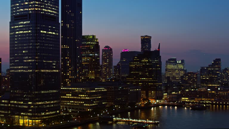 Jersey City along the Hudson River, illuminated at night. Aerial video with the backward-panning camera motion.