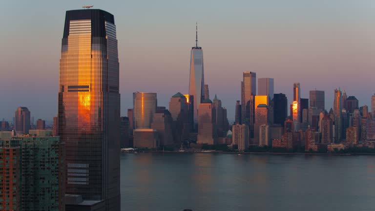 Paulus Hook in Jersey City with Goldman Sachs Tower and Lower Manhattan with One World Trade Center distant view, over the Hudson River at sunset. Aerial video with the  forward camera motion.