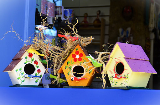 Beautiful handmade colorful wooden birdhouses on the blue window