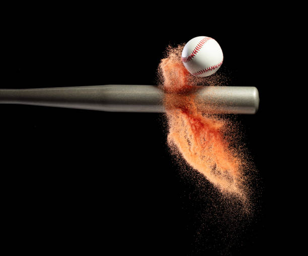 istock Baseball player hit ball with silver bat and sand soil explode in air. Baseball players in dynamic action hit ball smoke tail. Black background isolated freeze action 1584069383