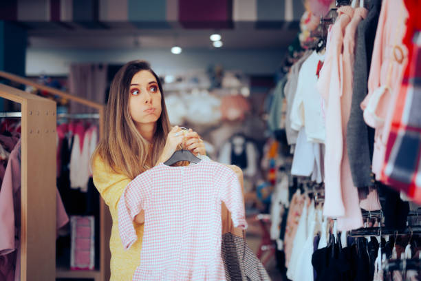 istock Funny Mom Choosing Between Two Dresses for her little Girl 1584077805