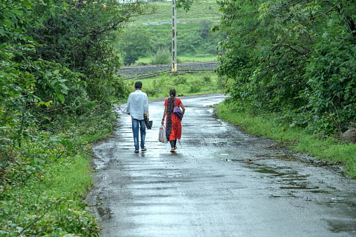 Pune, India - July 30 2023: A couple walking down a rural road during the monsoon season at Kamshet near Pune India.