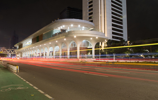Image of light trail on the road in front of public bus station.