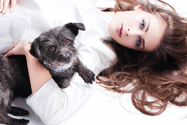 young elegant woman lie down with small dog in her arms