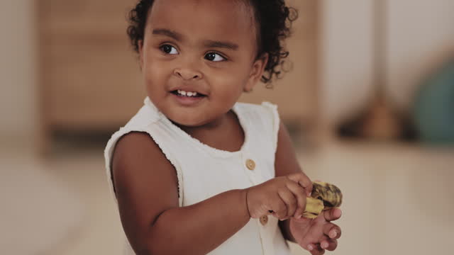 Cheerful black baby girl eat a banana
