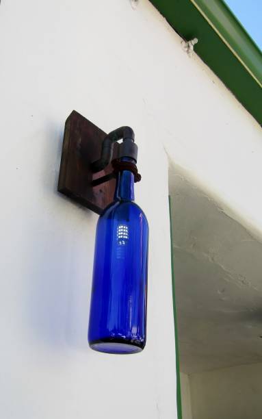 Dark blue glass wine bottle lantern on the white building wall
