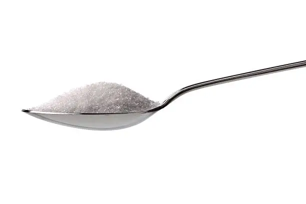 Sugar or salt on a teaspoon isolated on white
