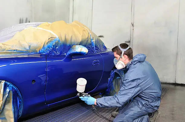 Photo of Worker painting a car.