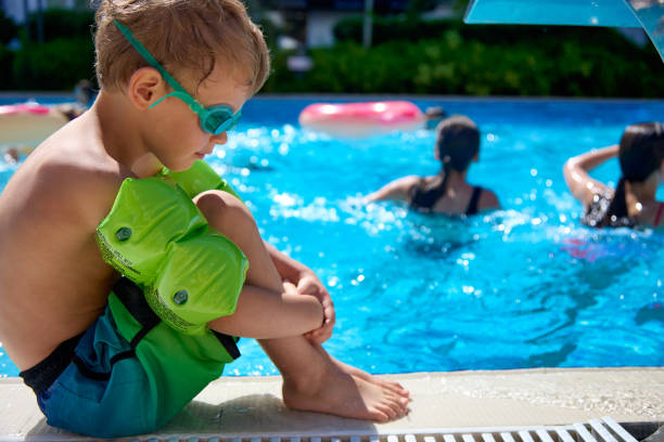 criança triste em equipamento de natação assiste adultos nadando em uma piscina profunda - mergulho autónomo - fotografias e filmes do acervo