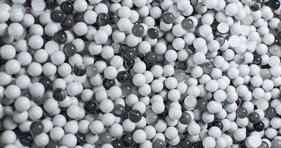 An up-close view unveiling an assemblage of black and white plastic and glass spheres strewn about, displaying intricate designs and varying textures.