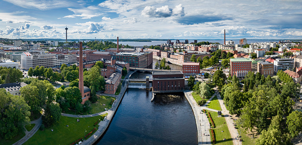 Tampere Cityscape Aerial Panorama in Summer under blue sky with fluffy cloudscape. Tammerkoski River and Hydroelectric Tammerkoski Waterfall in the Panorama Center. Finlayson Complex on the left, Näsinneula Observation Tower in the background. Tampere, Tammerkoski River, Finland, Nordic Countries, Scandinavia, Northern Europe