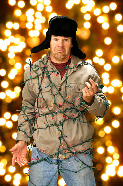 Christmas lights Funny confused man wrapped in colorful Christmas lights tangled photos stock pictures, royalty-free photos & images