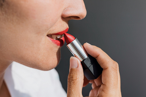 Latin adult Woman applying lipstick and painting her lips in color red at home in Mexico Latin America, hispanic people