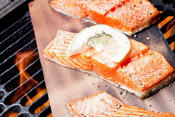 Three Grilled Salmon Filets on Cedar Plank Three wild-caught salmon filets on a cedar plank in a backyard grill.  Fist is bright reddish orange and is topped with lemon, dill and cracked pepper file_thumbview_approve.php?size=1&id=19631280 sockeye salmon filet stock pictures, royalty-free photos & images