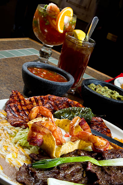 Bacon Wrapped Shrimp,  Grilled Chicken and Skirt Steak, Mexican Style with salsa, guacamole, iced tea and shrimp cocktail in the background