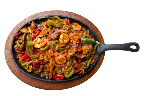 Shrimp, Beef and Chicken Fajitas on a hot skillet with onions, peppers and mushrooms