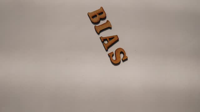Bias - word from wooden letters, personal opinions prejudice bias concept, random letters around on white background