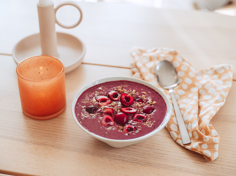 Smoothie bowl served on table with cherries and blueberry