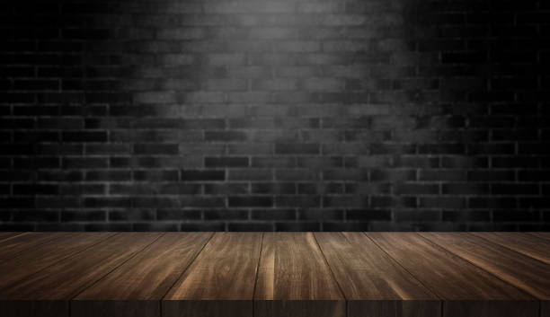 istock empty old wood table at foreground with black brick wall in dark room background for product placement. rustic wooden table with light from above. 1584543601