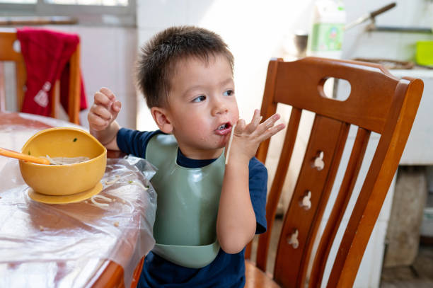 istock Toddler eating his meal using hands in an open rural kitchen setup while visiting his grandparents 1584559030