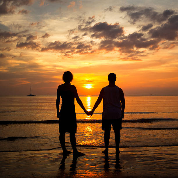 istock Young couple holding hands on the sea beach at sunset 158459464