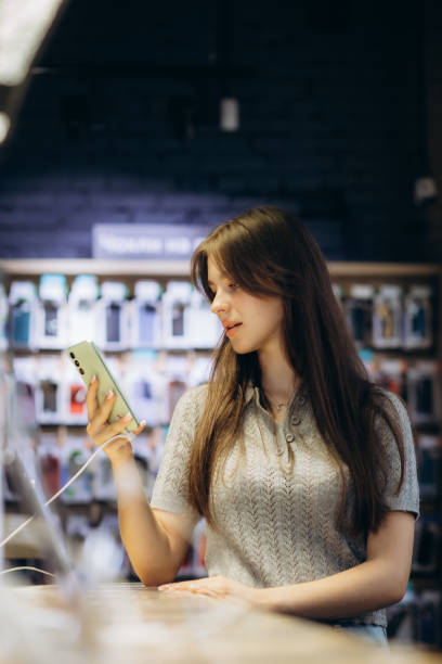 istock Woman choosing phone at technology store 1584624755
