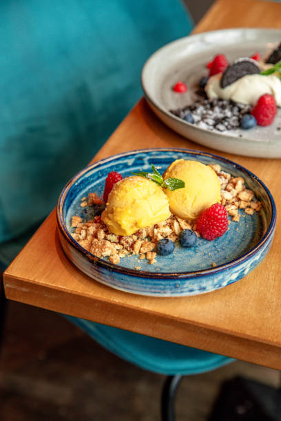 two Ice Cream Dessert plates with Mango Ice cream, berries and cookies and cream