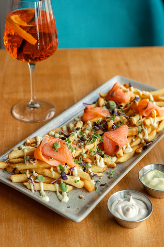 Loaded fries gourmet food with salmon lox, mayo and wasabi nuts served in restaurant with drinks