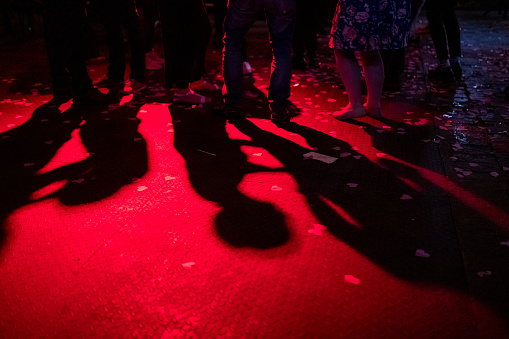 Shadows of dancing people show up in red light on a dance floor.