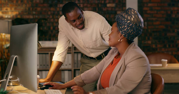 istock Business people, computer and support, planning or teamwork with online marketing or workflow management at night. Professional african man and woman talking, helping and advice on desktop in office 1584665342