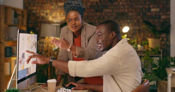 istock Business people, computer screen and teamwork, planning or support for marketing solution and website design at night. Professional graphic designer, african man and woman manager helping on desktop 1584665858