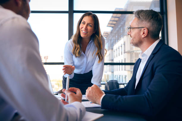 istock Business Team Meeting Around Office Boardroom Table With Laptops Discussing Documents 1584674634