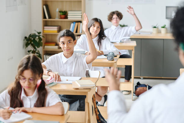 istock School children raising hands to answer at lesson 1584679657