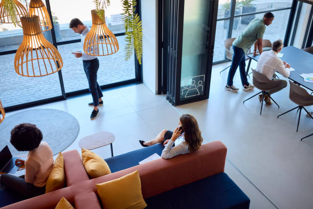 istock Overhead View Of Modern Open Plan Office With Staff Working Around Table And Breakout Seating Area 1584683157
