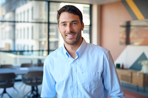 Portrait Of Smiling Businessman Standing In Empty Office