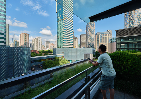Man overlooking Shanghai city skyline from rooftop balcony