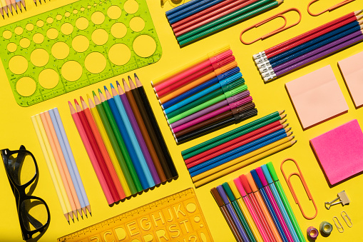 From above of assorted colorful office and school stationery placed on blue background