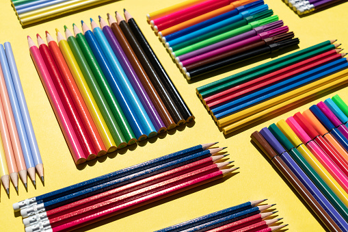 Colorful pen and pencils flat lay on yellow background